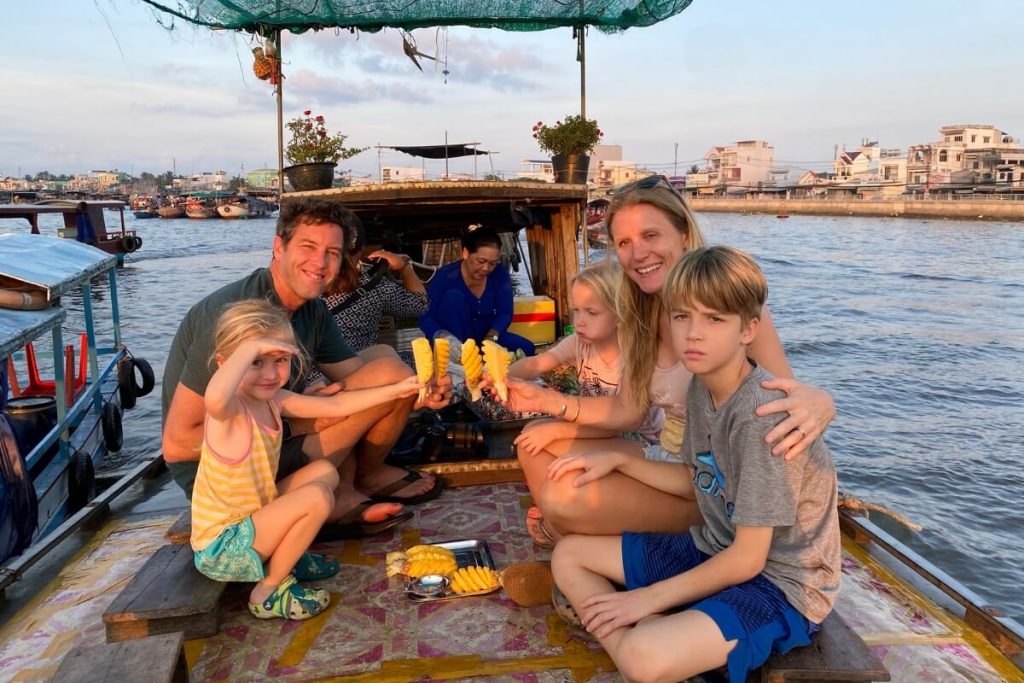 a family eat pineapple in a boat - mekong delta tour 7 days